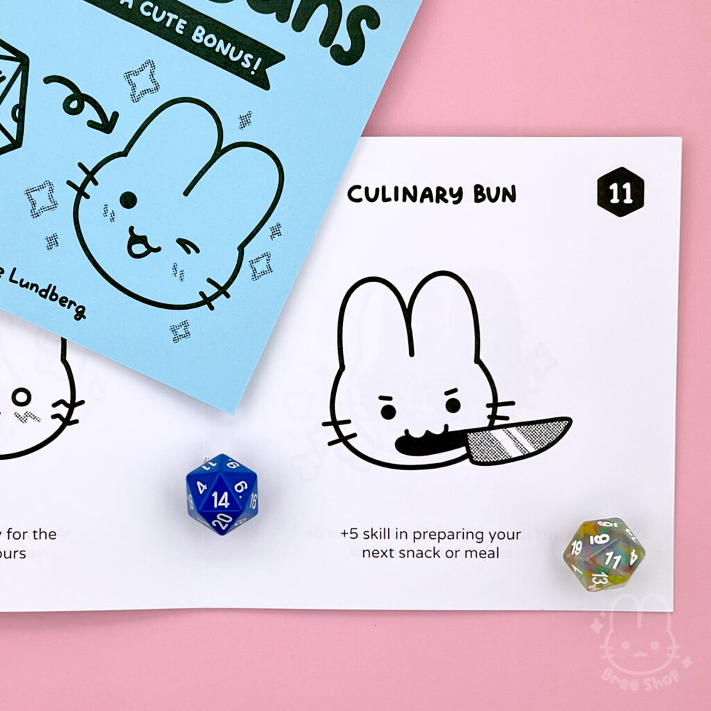 Photo of a Lucky Bun zines laying open showing a numbered page of a cute illustrated black and white bunny face and their bonus. This one is a "culinary bun" holding a knife and says +5 skilling preparing your next snack or meal.